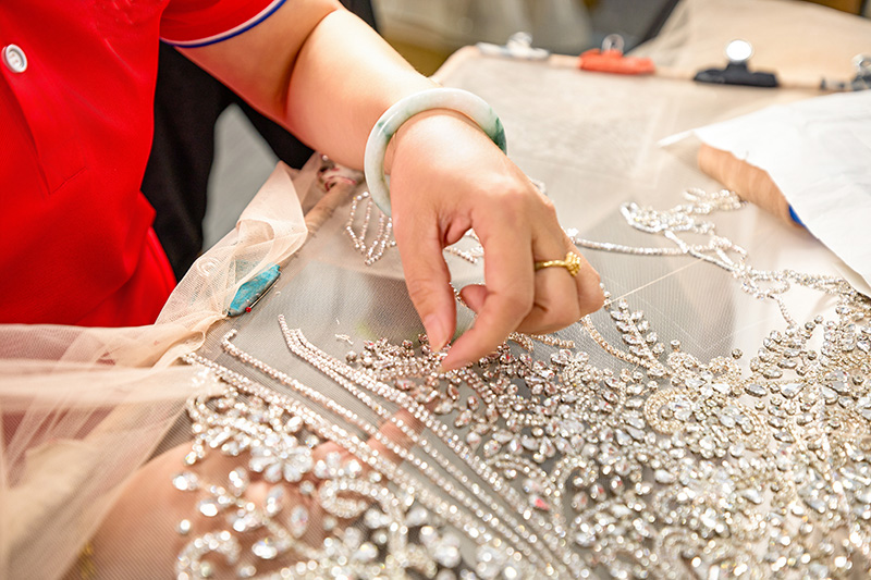 Artigiana che applica le paillettes a mano su un tulle